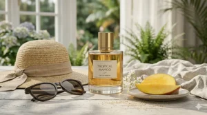 A flat lay of summer holiday essentials including a sun hat, sunglasses, and a mango-scented perfume.