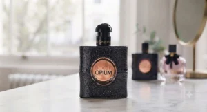 A detailed shot of the glittery black YSL Black Opium bottle standing on a marble surface, with soft natural lighting.